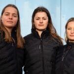 Three rowers stare at the camera. They are onshore as they prepare to row Pacific Ocean unsupported