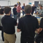 People gather around a tutor in a workshop on a TMS workshop / learning day