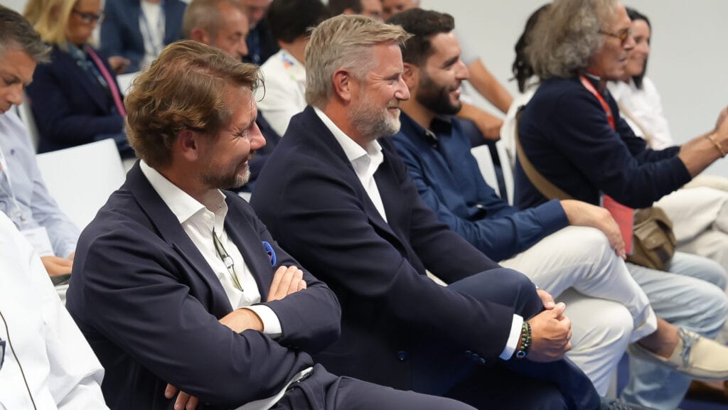 Men sitting in chairs smiling pictured from the side