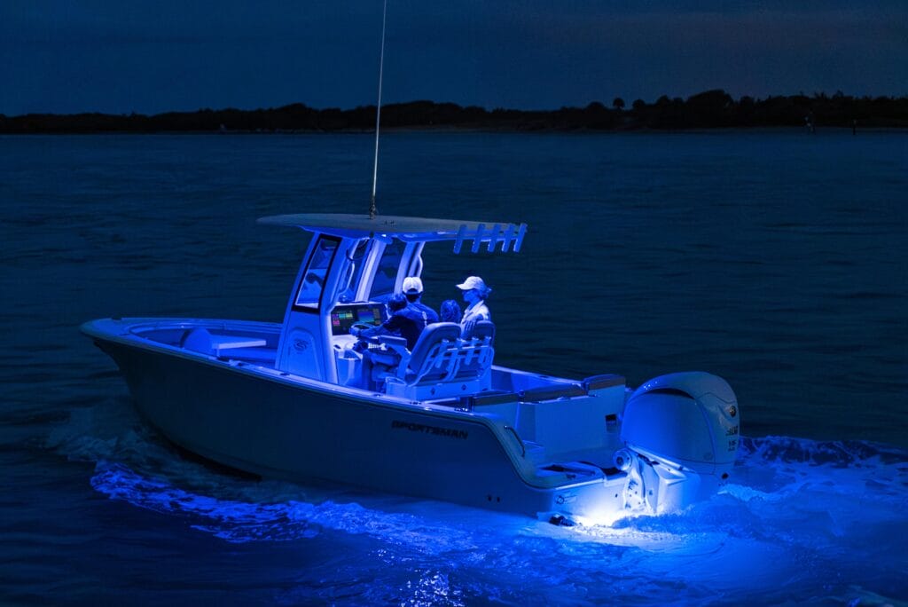 Small recreational fishing leisure boat at night lit up with blue LED lights at console and transom