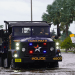 Police vehicle in water on road in Tampa as Hurricane Helene threatens to cancel IBEX