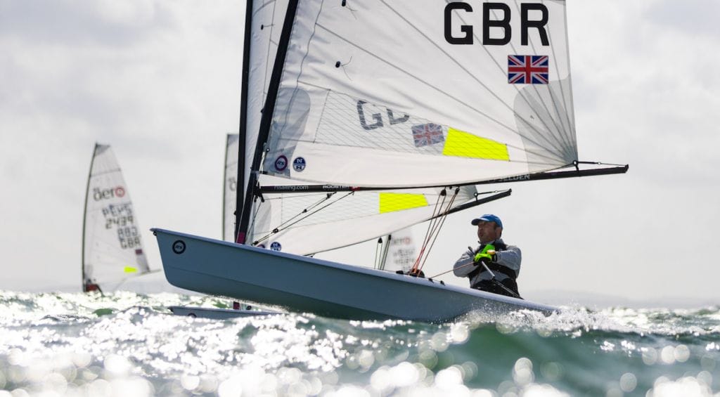 person sails an RS Aero with sunshine glinting on water