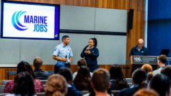 two people talk in a lecture theatre in front of a crowd