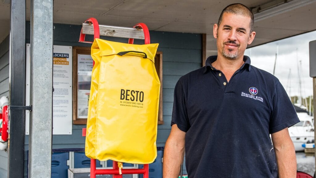 Man stands beside red ladder which has a yellow bag attached to it. This is new ladder design at Buckler's Hard Yacht Harbour