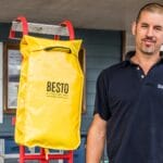 Man stands beside red ladder which has a yellow bag attached to it. This is new ladder design at Buckler's Hard Yacht Harbour