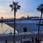 Superyacht berthed in Malaga with sun behind it and palm trees