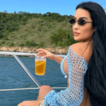 Lady with back to camera raises drink while sat onboard a boat.