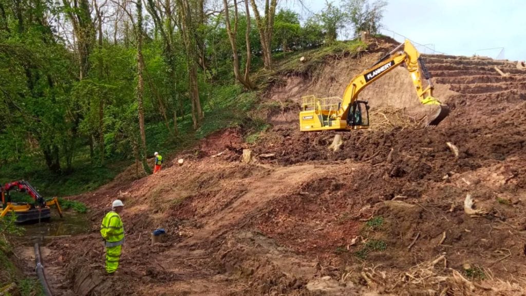 A digger in an embankment with soil as canals suffer from climate change