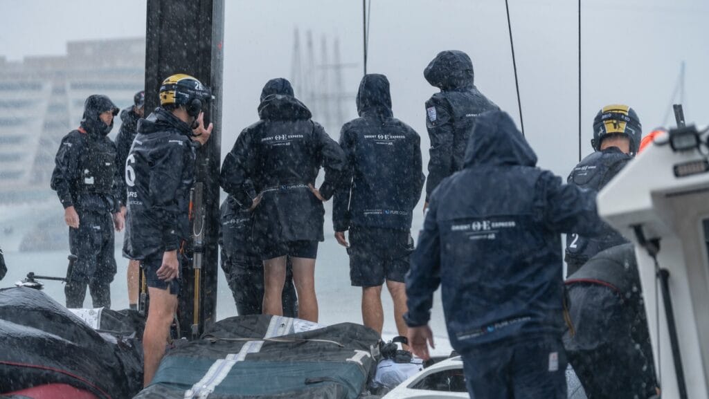 members of French America's Cup team on deck with backs to camera