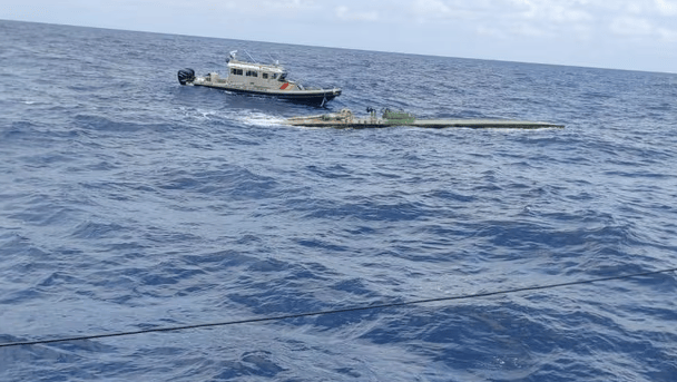 Narco sub bobs on ocean as small interceptor vessel approaches