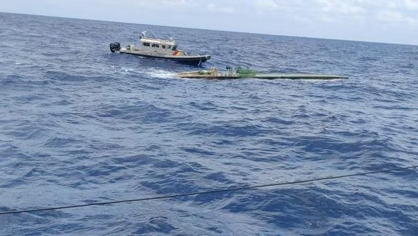 Narco sub bobs on ocean as small interceptor vessel approaches
