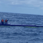 Low, slim narco sub caught smuggling drugs bobs around in ocean pictured with two people in orange lifejackets