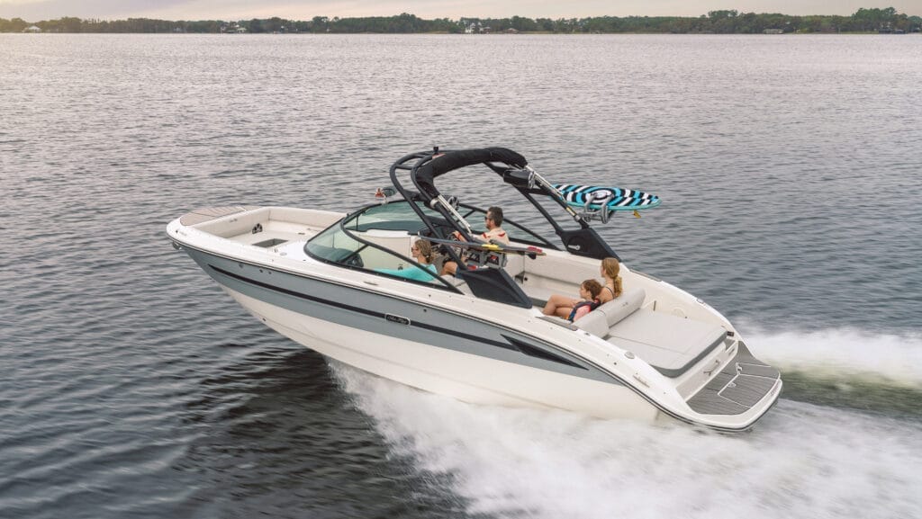 White sportsboat cruising across water with wake in foreground