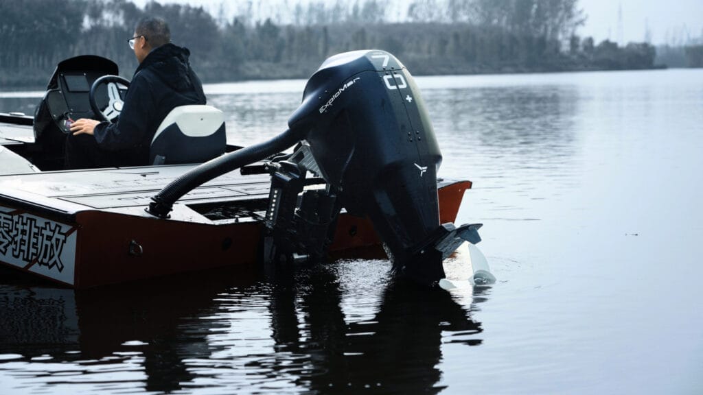 electric outboard from Explomar dips into smooth water behind jet black boat