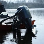 electric outboard from Explomar dips into smooth water behind jet black boat