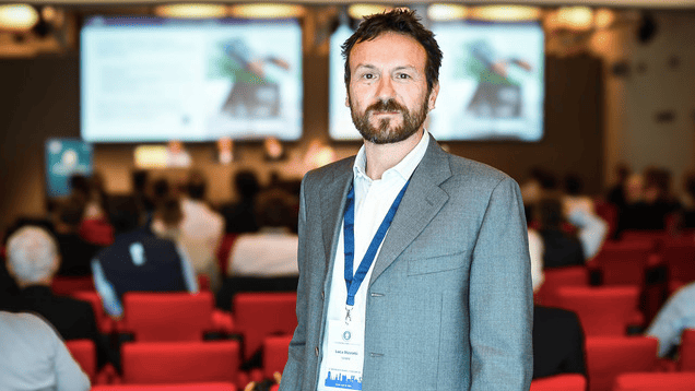 Luca Rizzotti, founder and president of the The Foiling Organization stands in lecture theatre and looks at camera