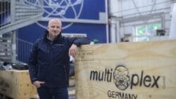 Marko Böhme standing in front of wooden multiplex logo