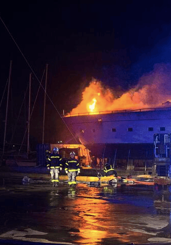 Firefighters at night watch flames rise above Sanlorenzo yacht