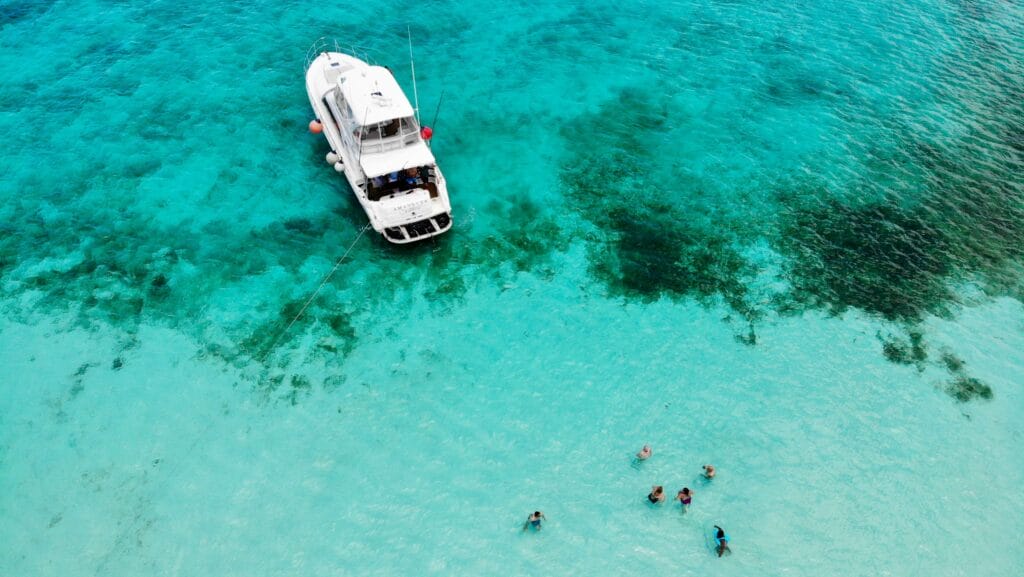 Aerial view of white motor boat in clear water with swimmers having a jolly time