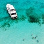 Aerial view of white motor boat in clear water with swimmers having a jolly time