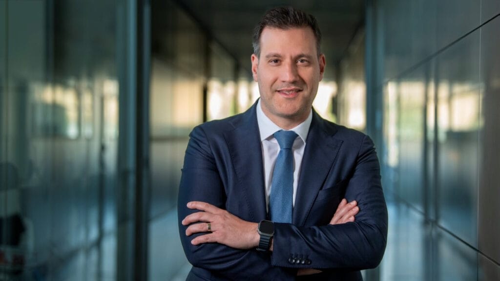 Man with crossed arms in suit smiles at camera