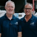 Two men in blue polo shirts in boat factory
