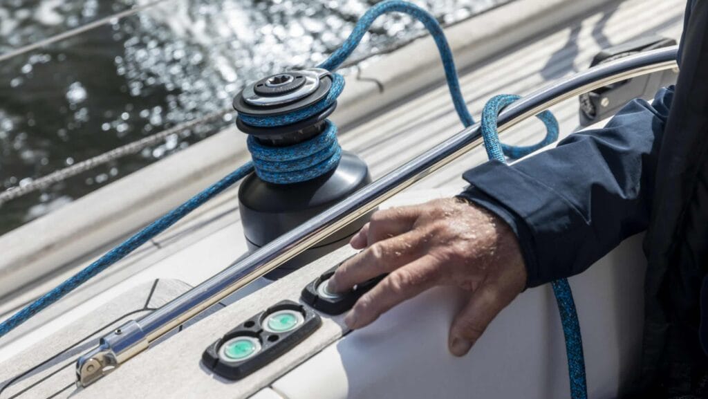 Sailors hand by button winch on sailing boat