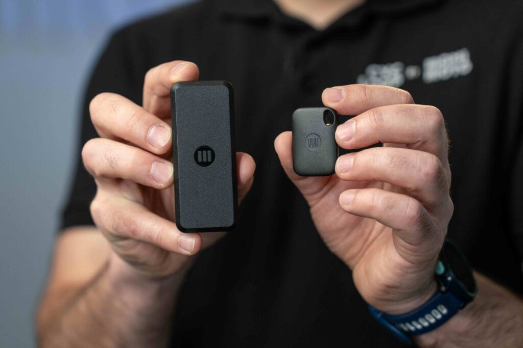 close up of hands holding two small black gadgets