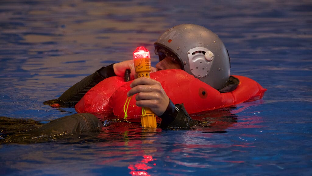 Person in lifejacket in water holds light