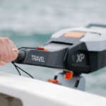 a hand on a Torqeedo electric outboard with water behind