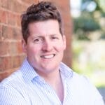 man in white business shirt leaning against a wall