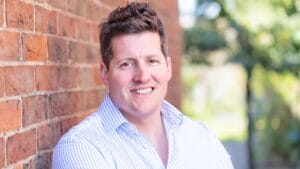 man in white business shirt leaning against a wall